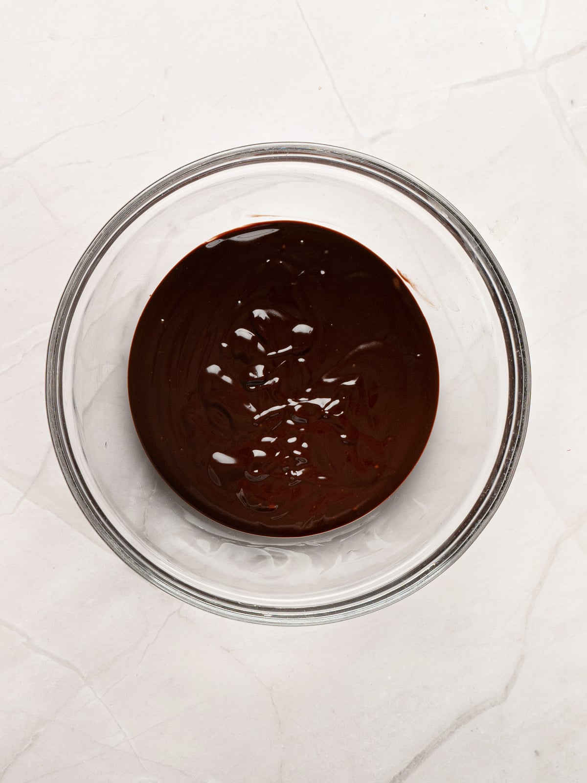 Smooth homemade chocolate dipping sauce made with melted chocolate chips and cream in a glass bowl, ready to serve with fresh churros.