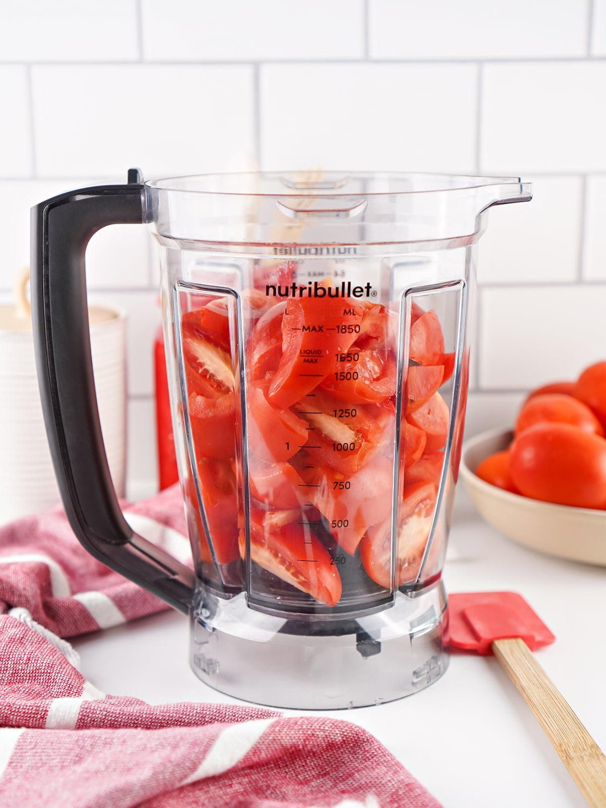 Quartered Roma tomatoes packed into a blender before being pureed for homemade tomato paste.