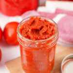 Jar of thick homemade tomato paste made from fresh Roma tomatoes.