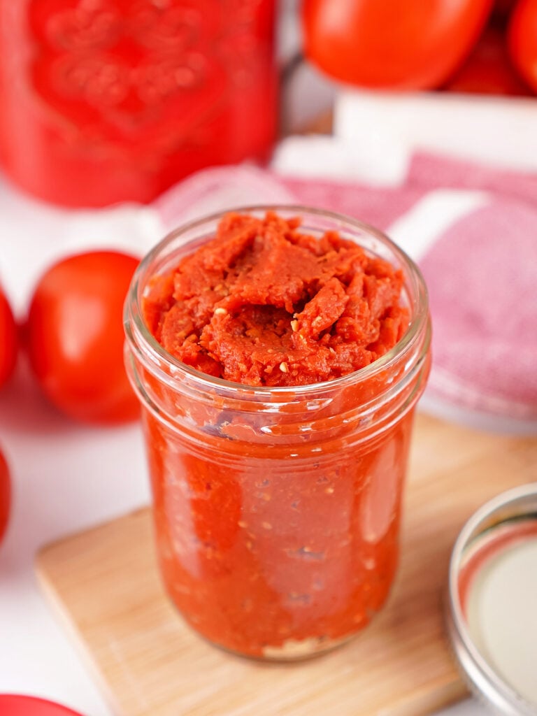 Jar of thick homemade tomato paste made from fresh Roma tomatoes.