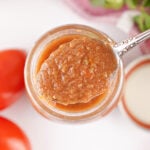 Close-up of a spoonful of smooth homemade restaurant style salsa over an open mason jar.