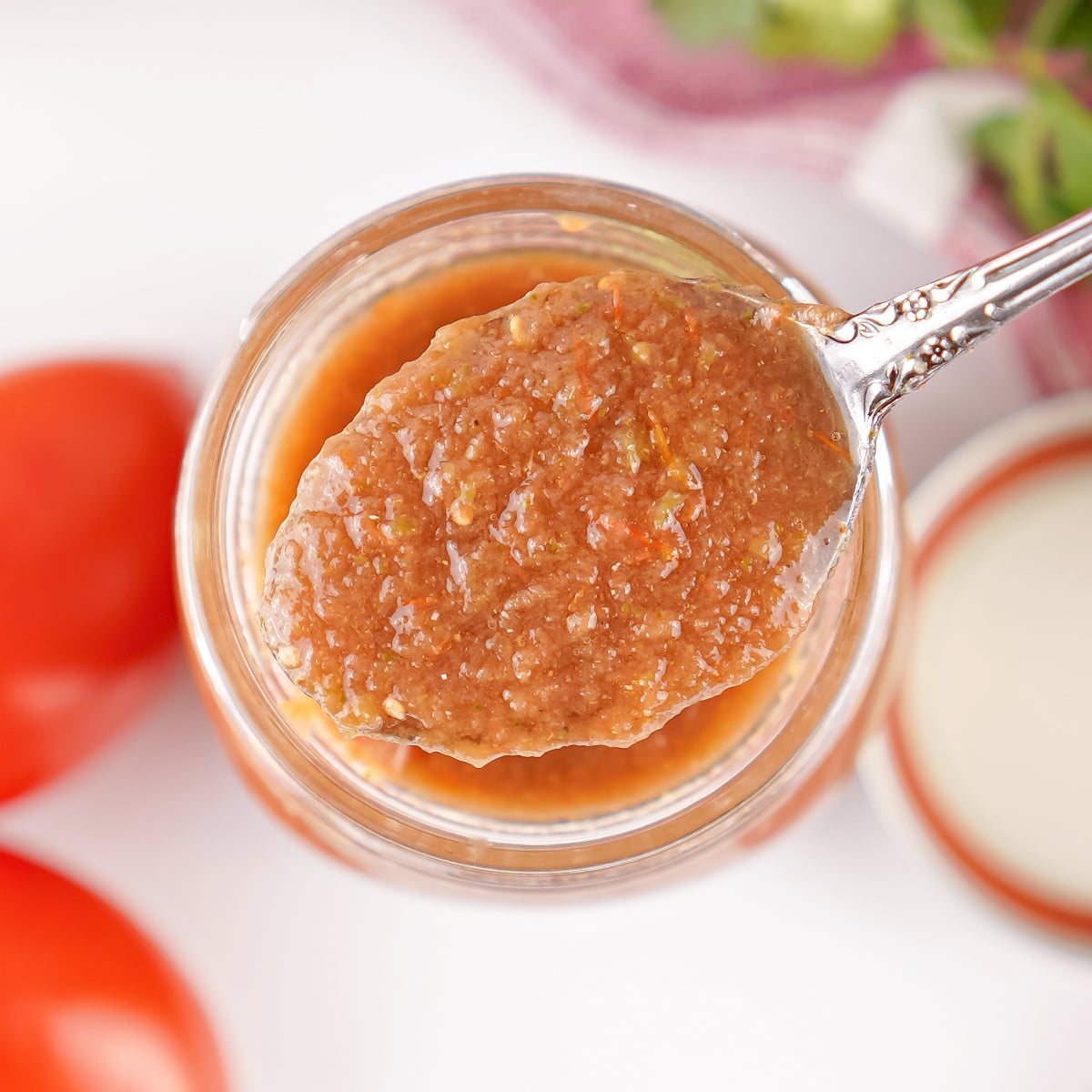 Close-up of a spoonful of smooth homemade restaurant style salsa over an open mason jar.