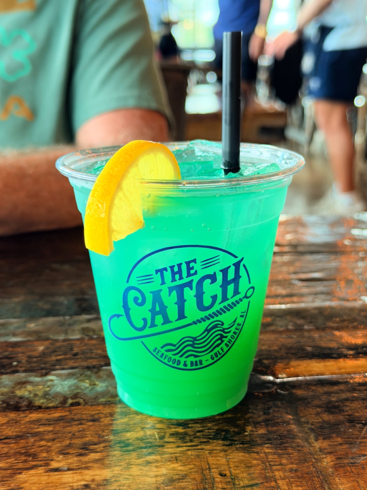 Bright blue cocktail with a lemon wedge and black straw at The Catch in Gulf Shores.