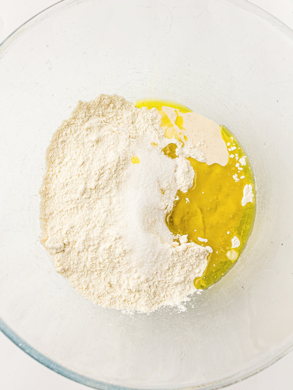 Flour, sourdough discard, oil, and salt combined in a large glass mixing bowl.