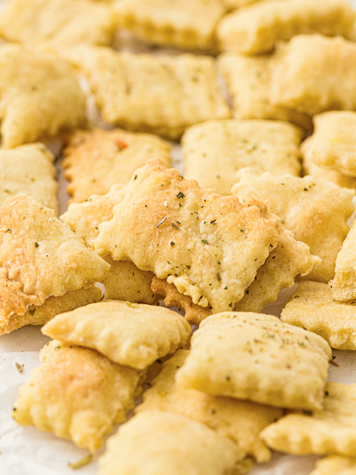 Close-up of golden sourdough discard crackers sprinkled with dried herbs.